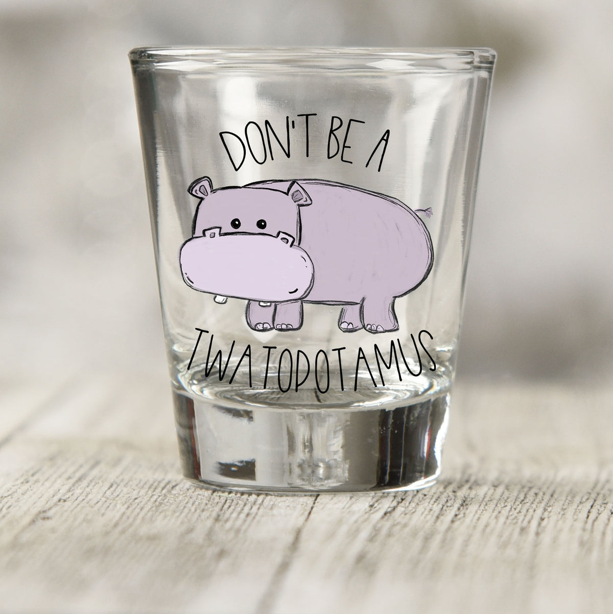Don't Be a Twatopotamus shot glass UV DTF transfer with lavender cartoon hippo on a clear shot glass