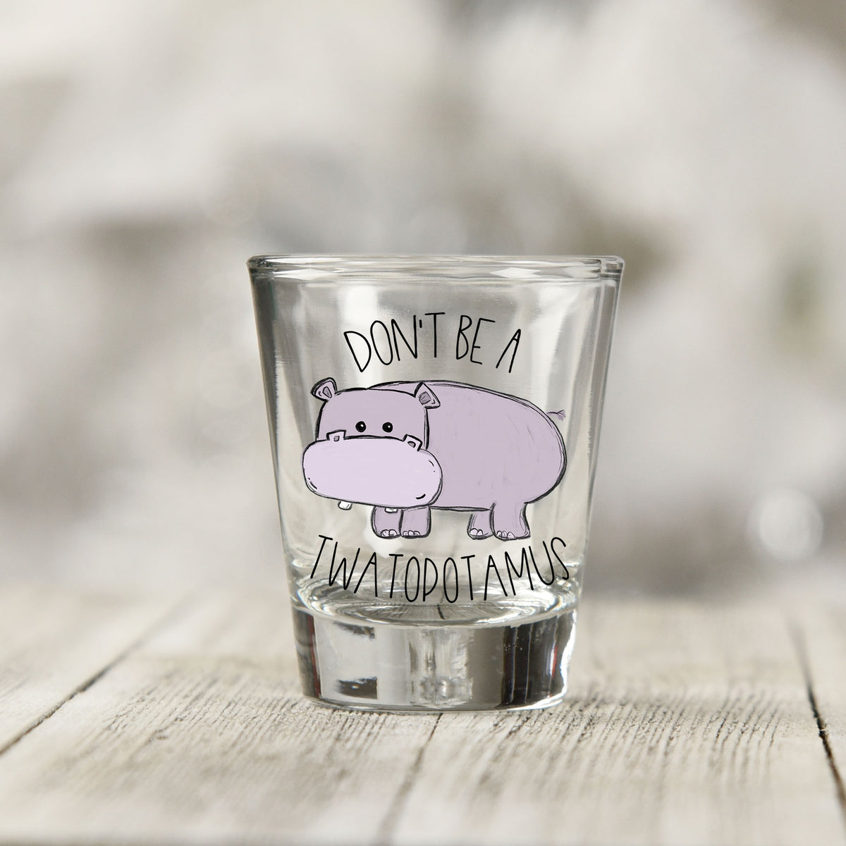 Close-up of the Don't Be a Twatopotamus UV DTF transfer on a clear shot glass