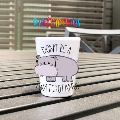 Don't Be a Twatopotamus UV DTF transfer on a white shot glass on an outdoor patio table