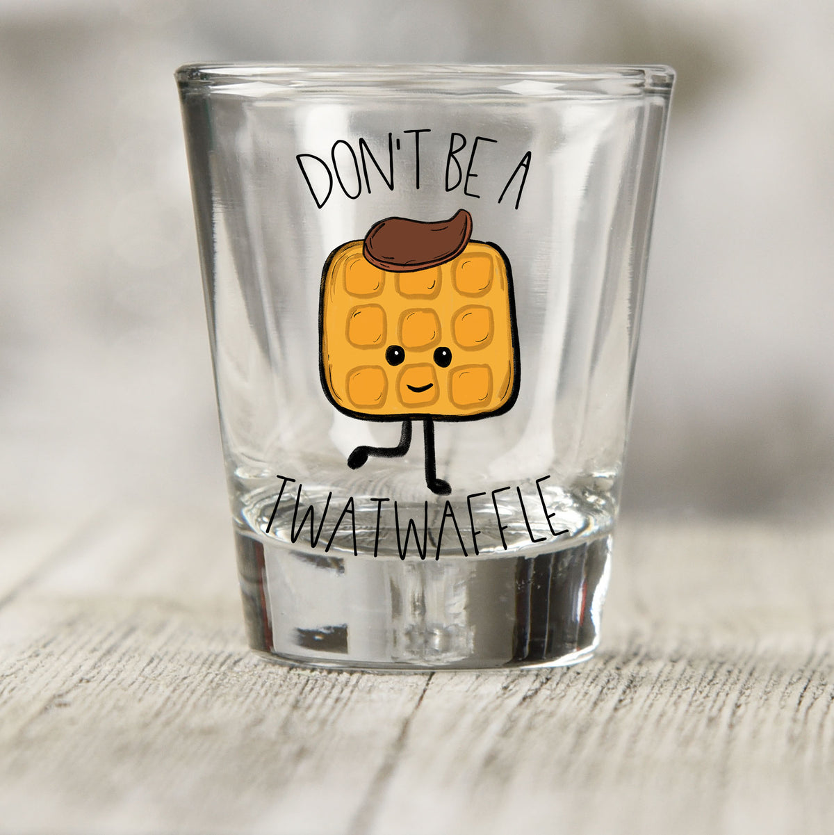 Don't Be a Twatwaffle shot glass UV DTF transfer with cartoon waffle character on a clear shot glass