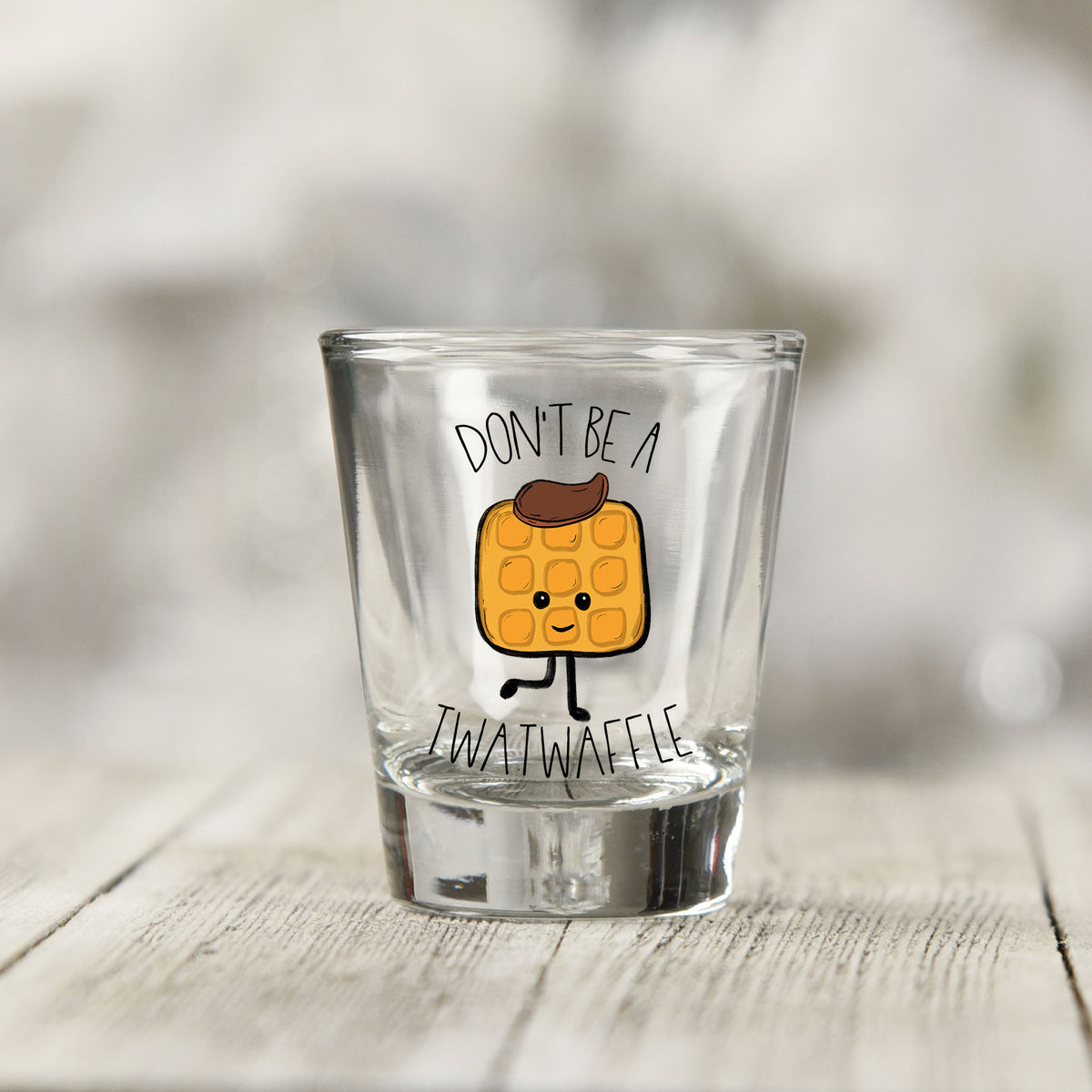 Close-up of the Don't Be a Twatwaffle UV DTF transfer on a clear shot glass