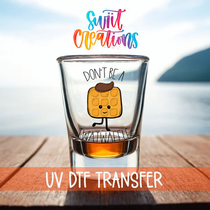 Don't Be a Twatwaffle shot glass UV DTF transfer on a filled shot glass on a dock by the water