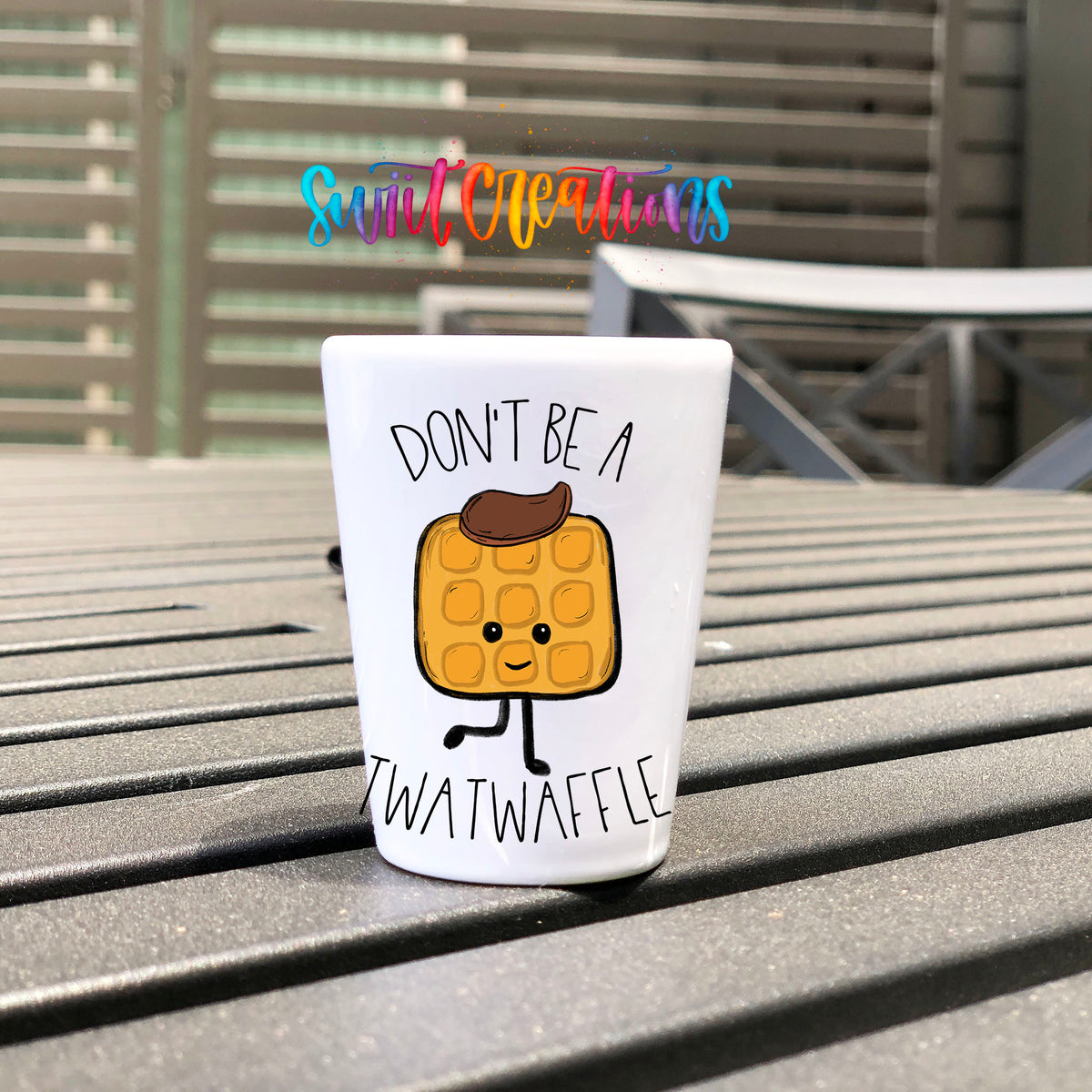 Don't Be a Twatwaffle UV DTF transfer on a white shot glass on an outdoor patio table
