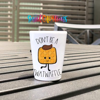 Don't Be a Twatwaffle UV DTF transfer on a white shot glass on an outdoor patio table