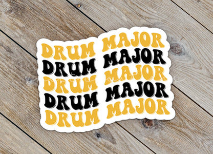Close-up of the Black and Gold Drum Major sticker on rustic wood