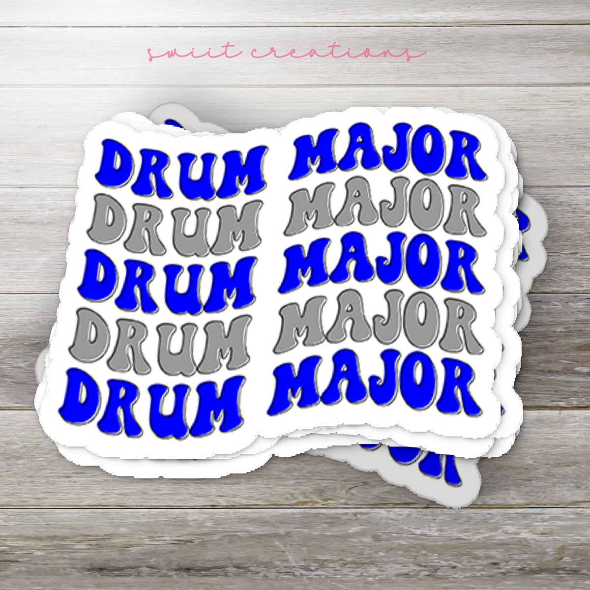 Stack of Blue and Silver Drum Major glossy stickers on a gray wood table