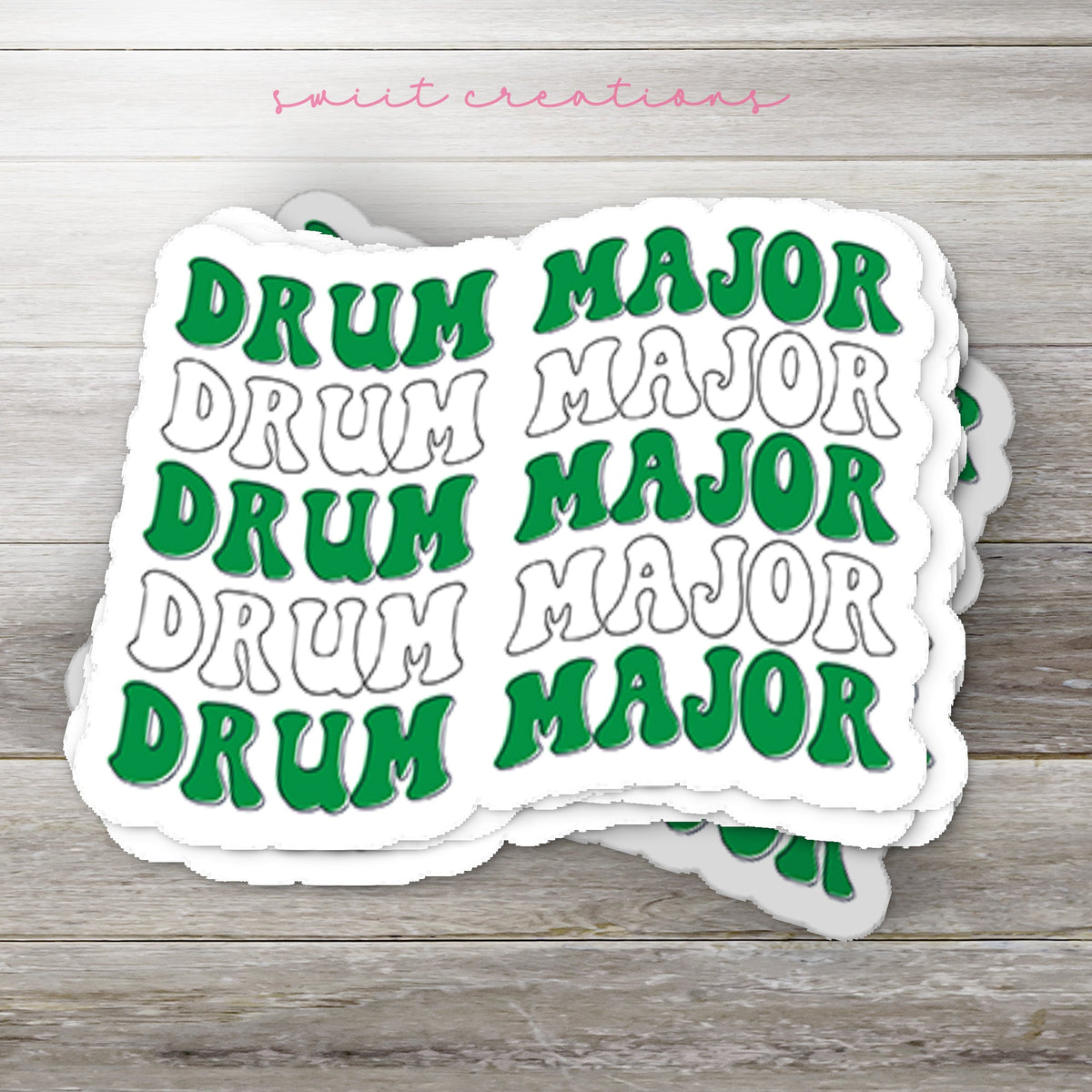 Stack of Green and White Drum Major glossy stickers on a gray wood table