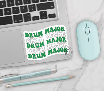 Green and White Drum Major vinyl sticker on a silver laptop next to a mint mouse and pens