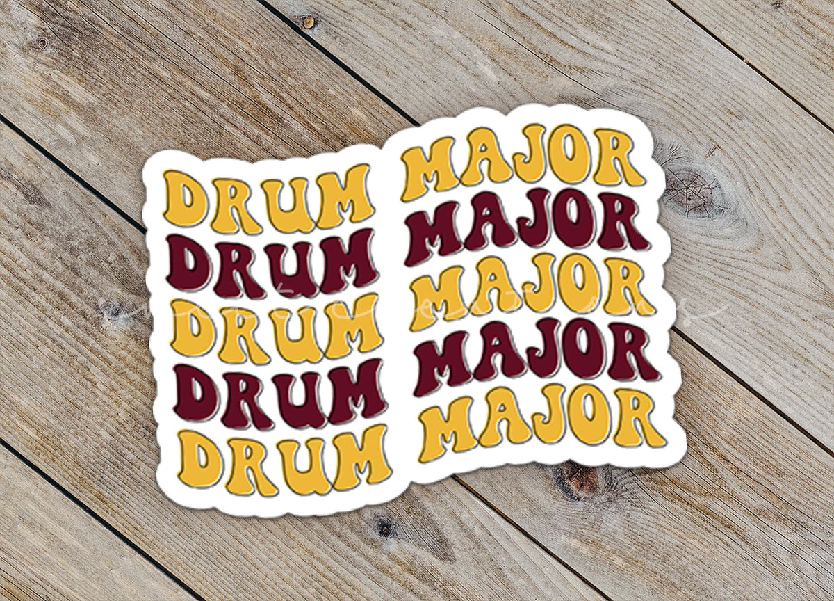 Close-up of the Maroon and Gold Drum Major sticker on rustic wood