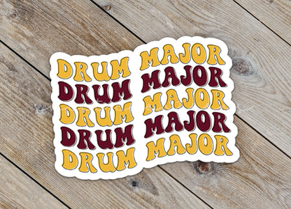 Close-up of the Maroon and Gold Drum Major sticker on rustic wood