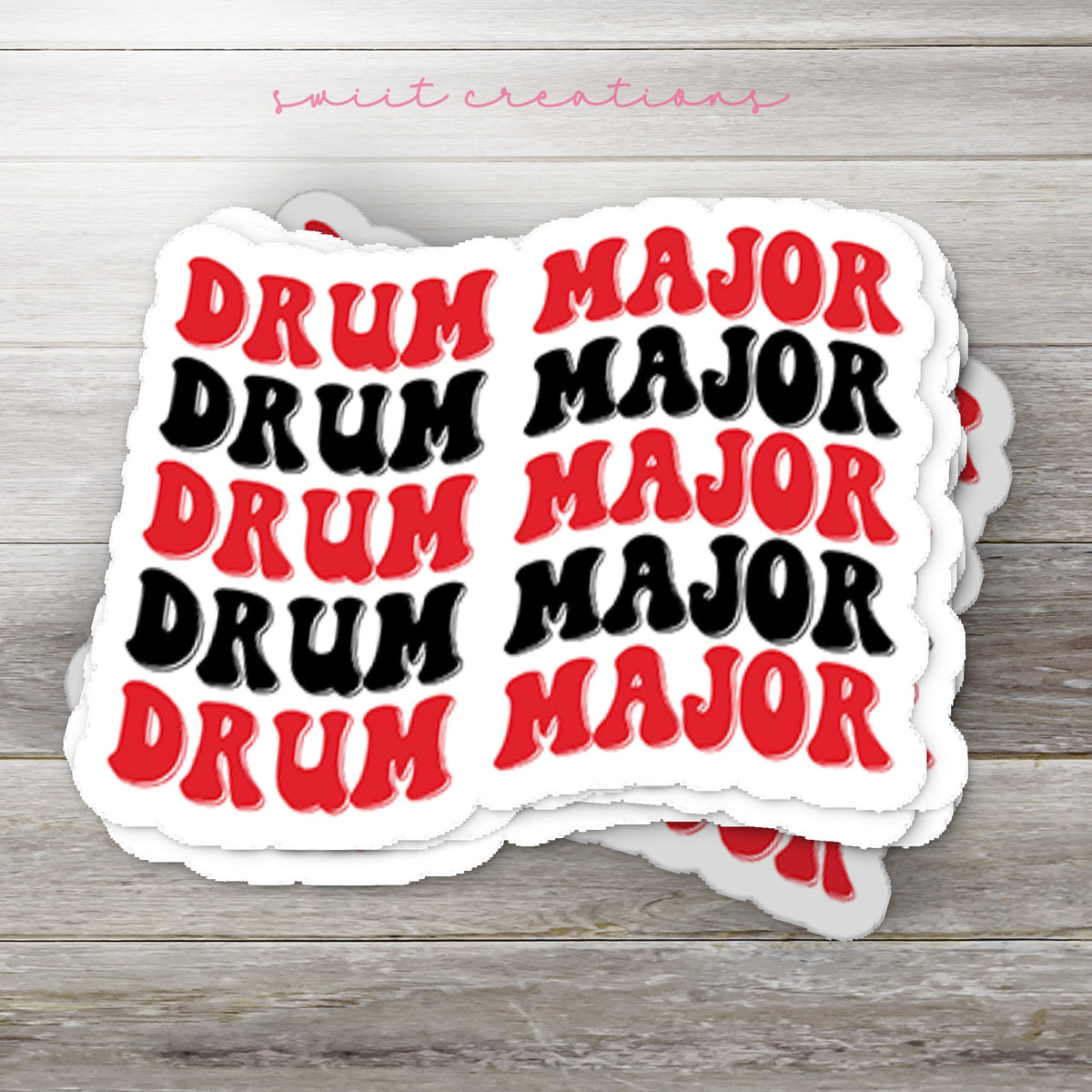 Stack of Red and Black Drum Major glossy stickers on a gray wood table