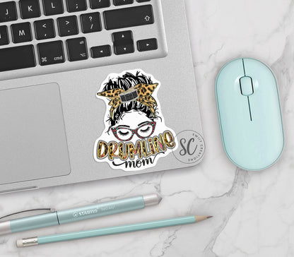 Drumline Mom vinyl sticker on a silver laptop next to a mint mouse and pens
