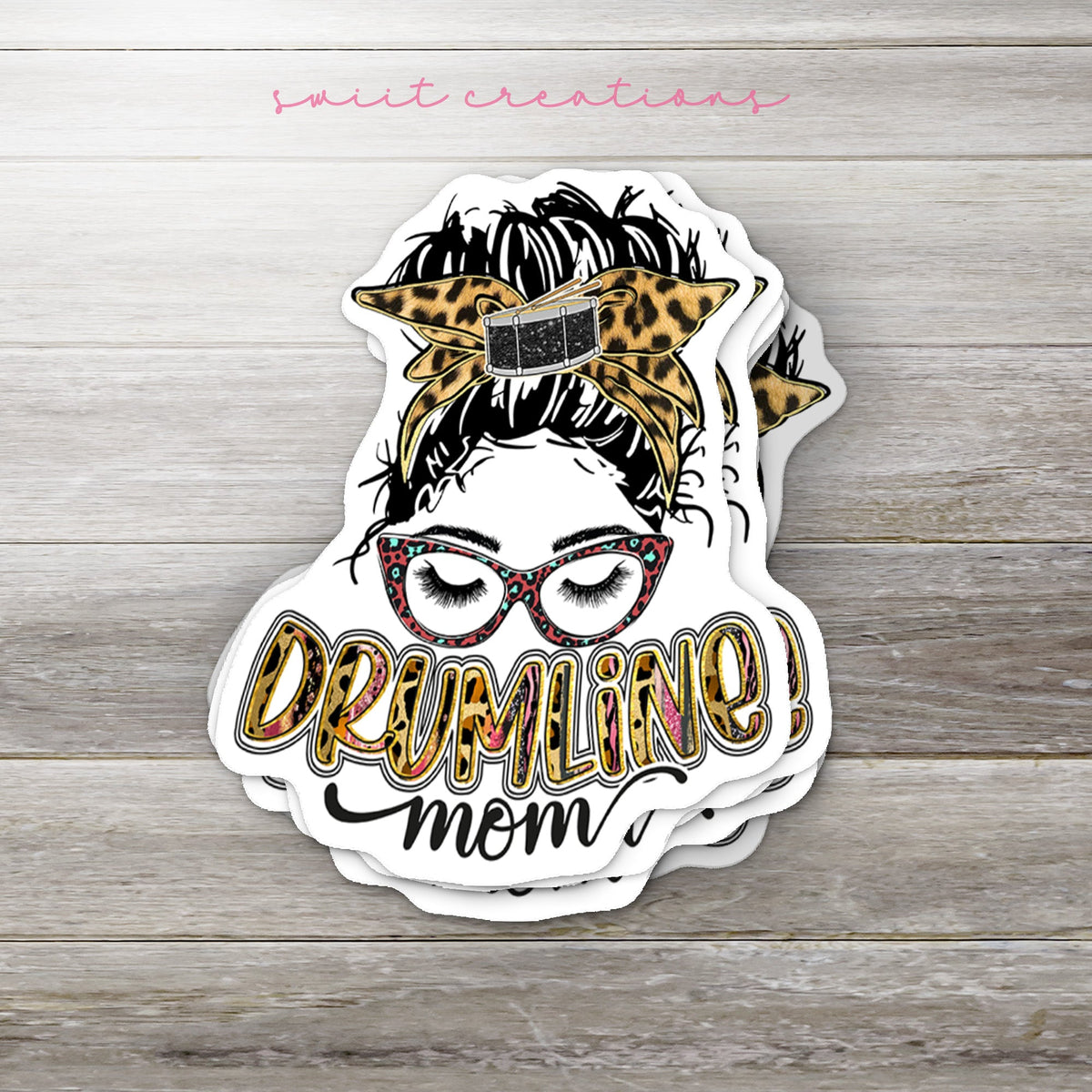 Stack of Drumline Mom glossy stickers on a gray wood table