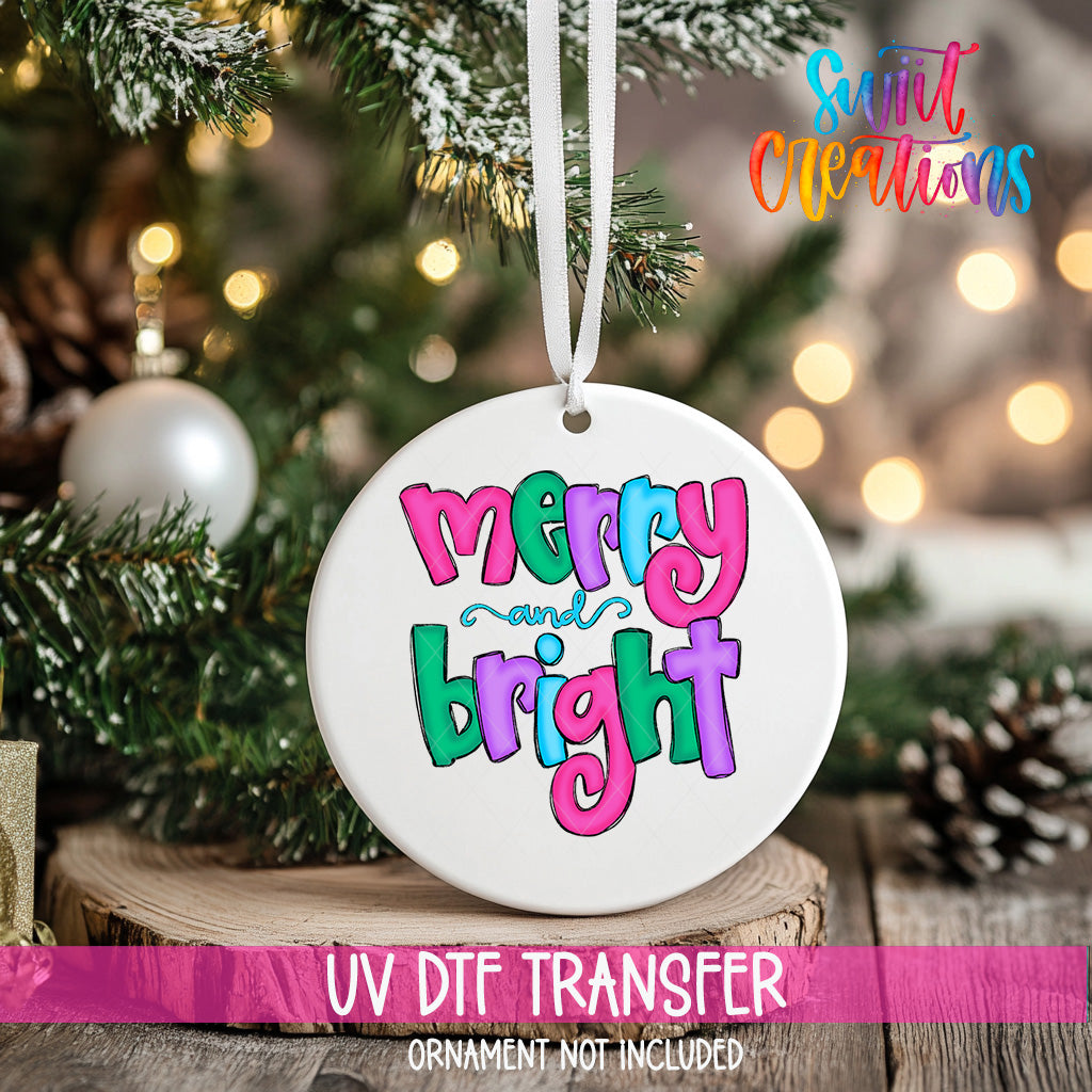 A white ceramic ornament with the text "Merry and Bright" in colorful letters hangs from a Christmas tree.