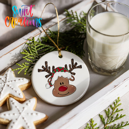 A white ceramic ornament with a cartoon reindeer wearing a Santa hat is displayed on a white tray, accompanied by a glass of milk and some cookies.