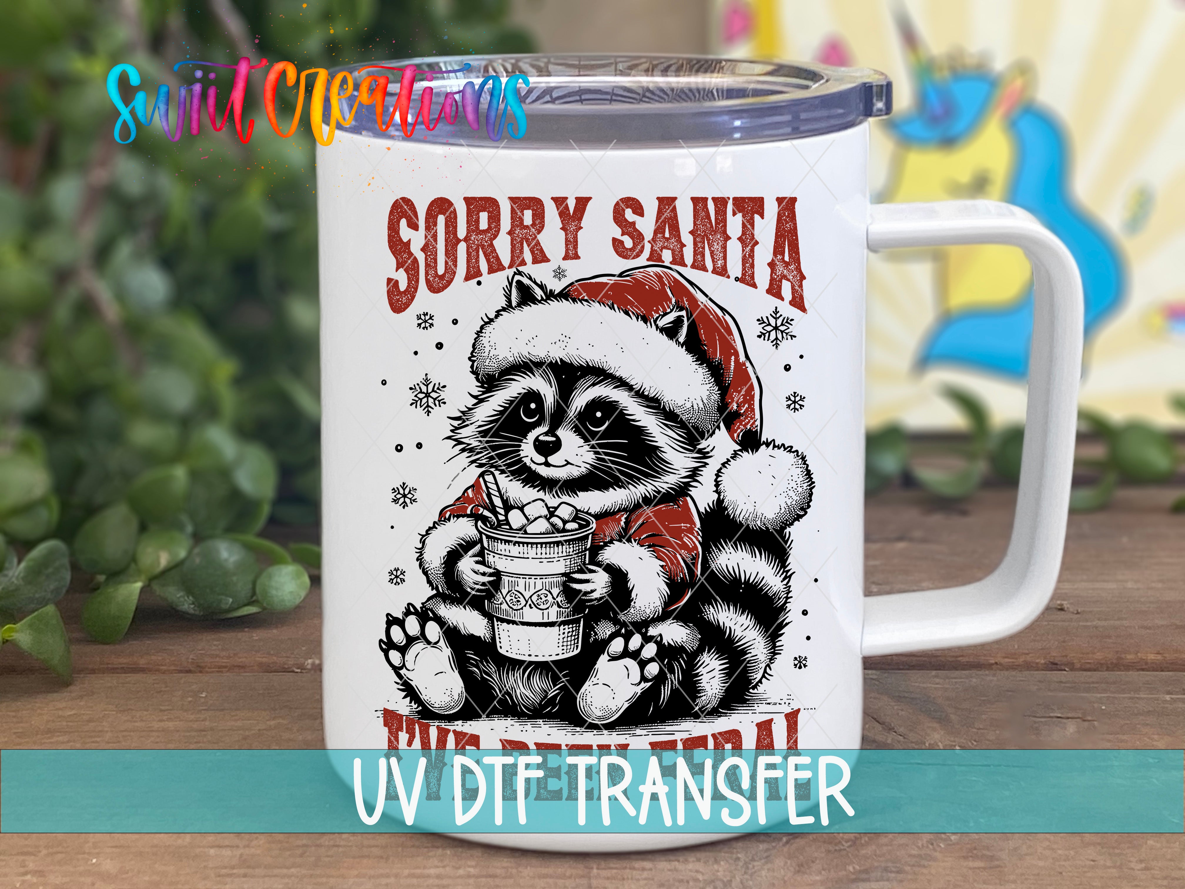 A mug with a raccoon wearing a Santa hat and holding a cup of hot chocolate, with the text "Sorry Santa" and "UV Dtf Transfer" printed on it.
