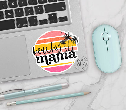 Beachy Mama vinyl sticker on a silver laptop next to a mint mouse and pens