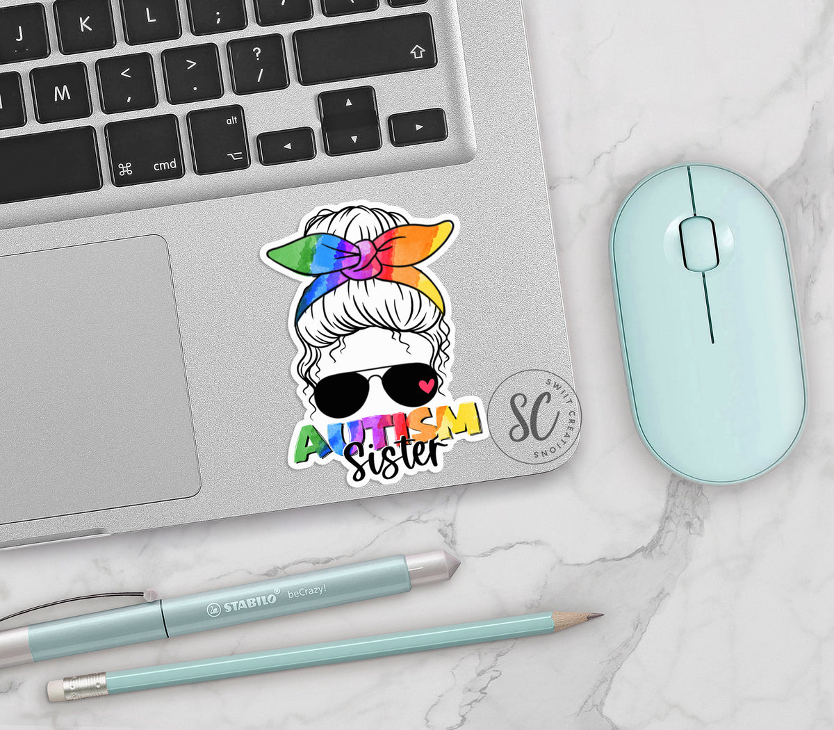 Autism Sister vinyl sticker on a silver laptop next to a mint mouse and pens