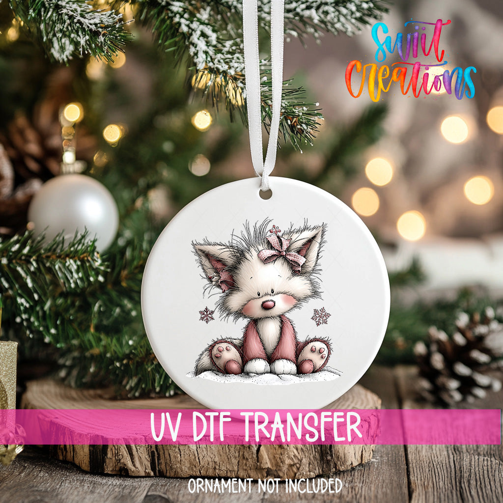 A white ceramic ornament with a cute cartoon cat illustration hangs on a Christmas tree.