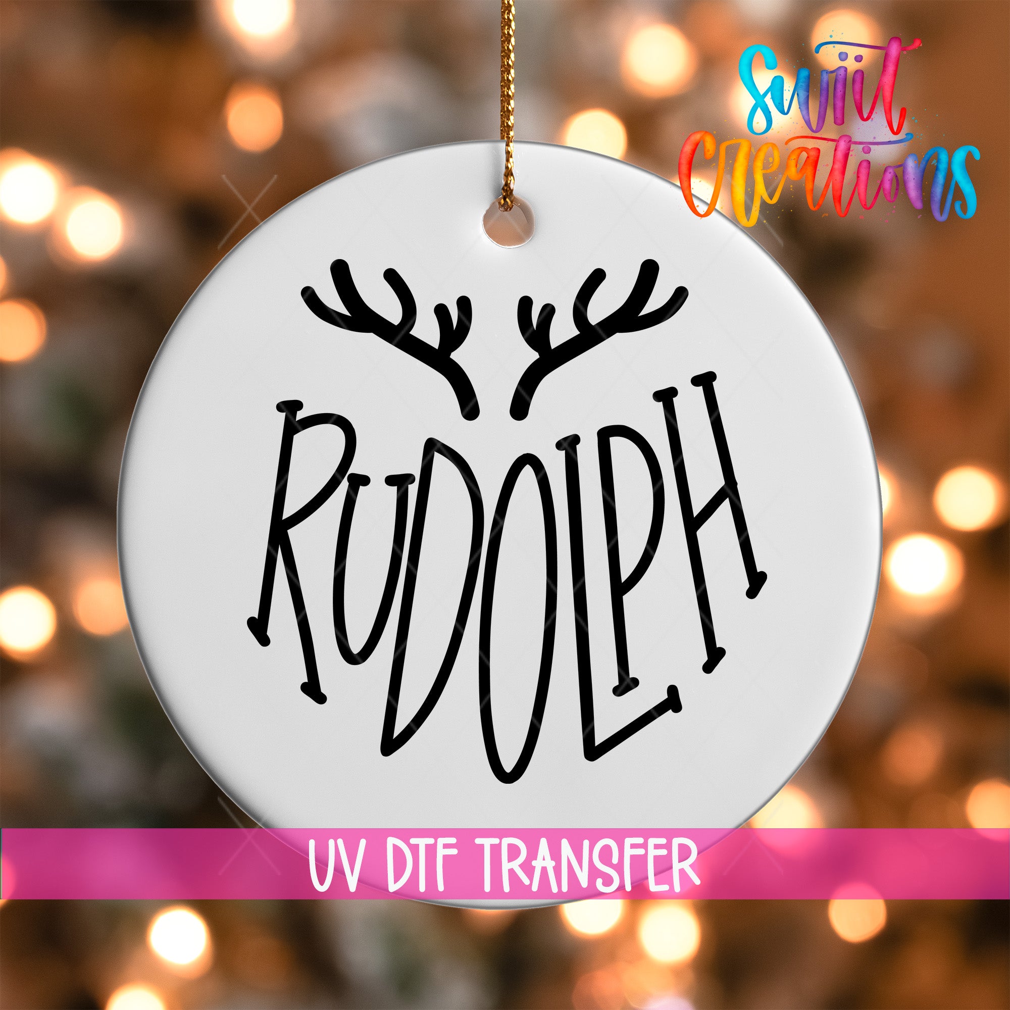 A white ornament with the word "RUDOLPH" written on it, hanging against a background of colorful lights.
