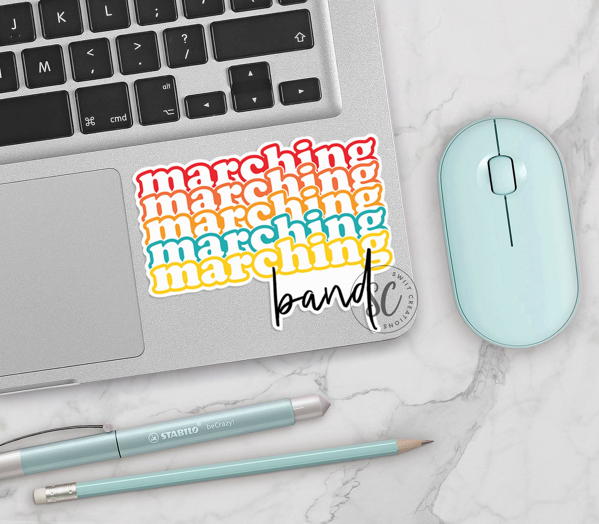 Retro Marching Band vinyl sticker on a silver laptop next to a mint mouse and pens