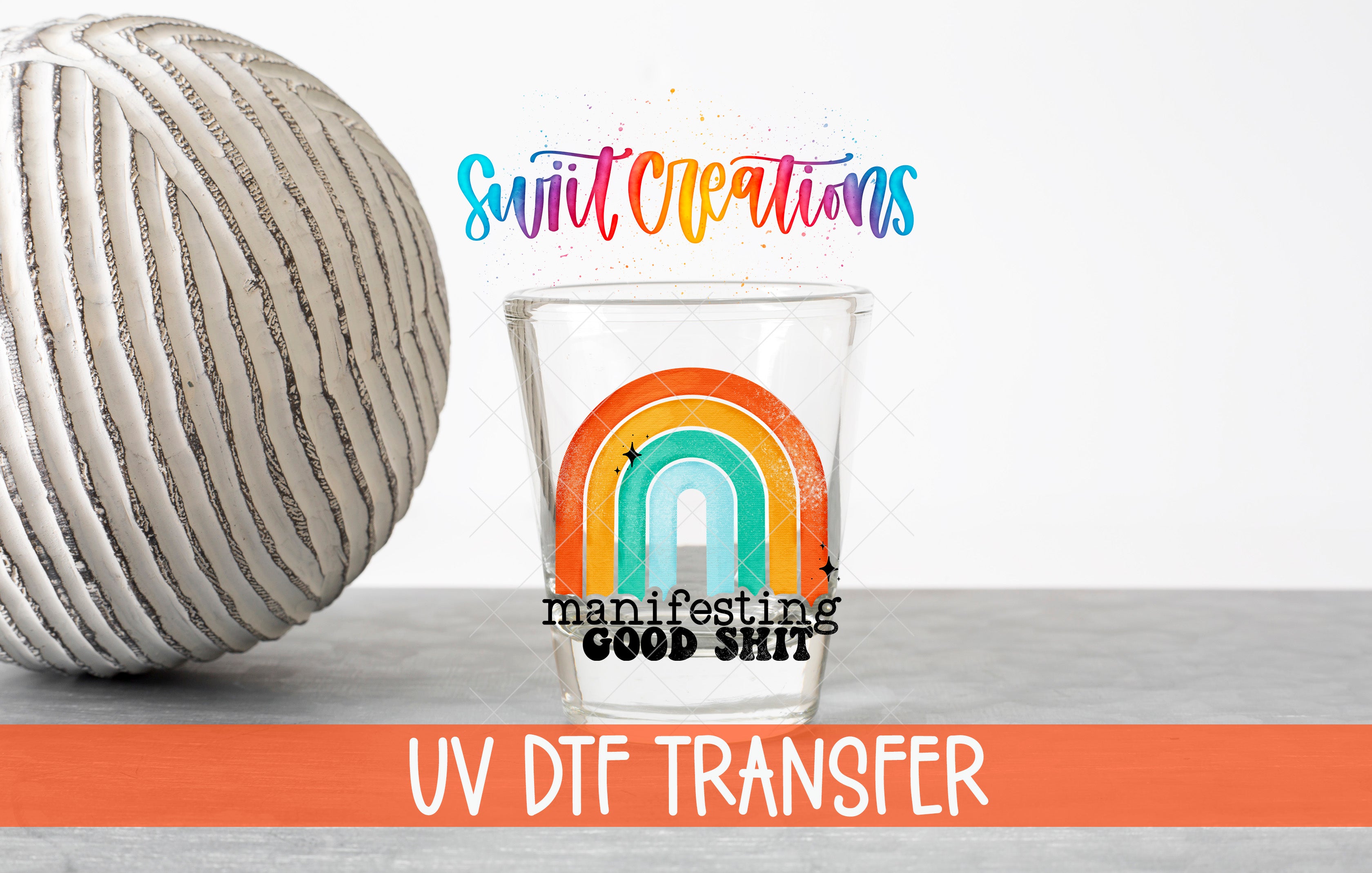 a glass with a rainbow design and the text "manifesting good shit" on it, along with a gray ball and the text "Swit Creations" and "UV Dtf Transfer" in the background.