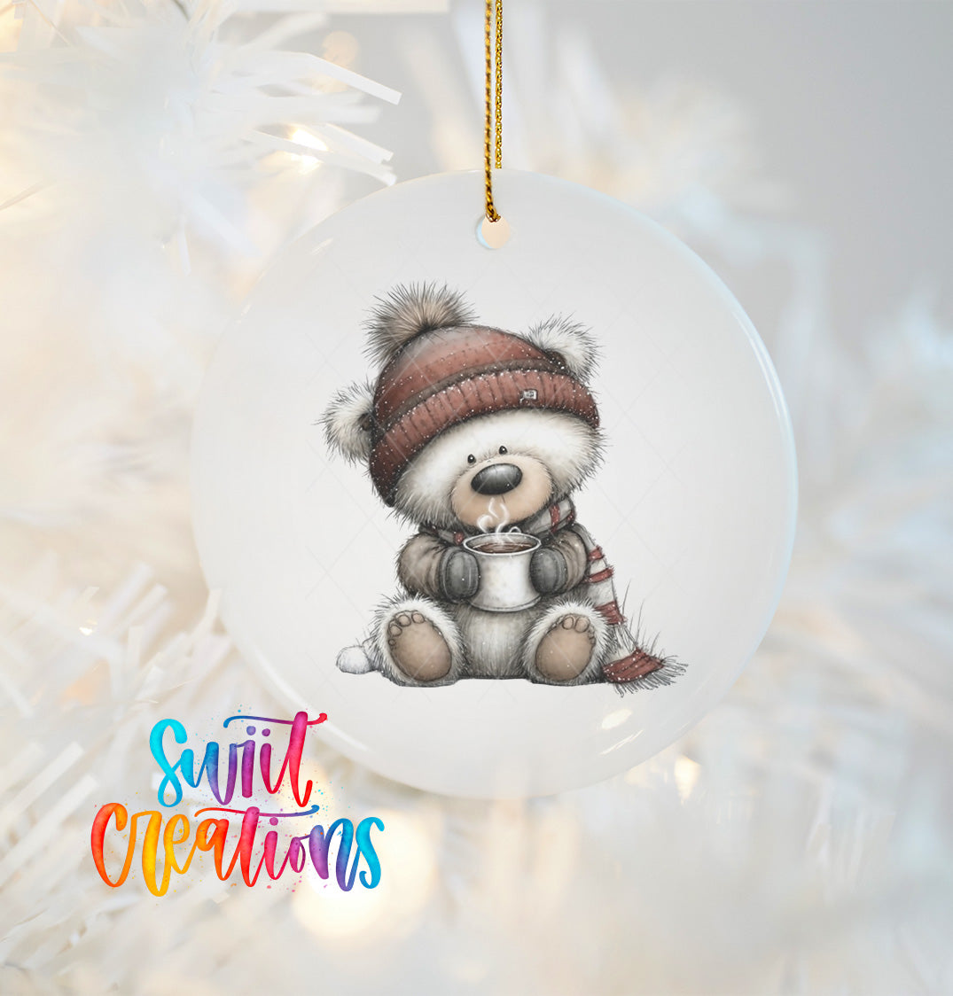 A white ceramic ornament featuring a cute teddy bear wearing a winter hat and scarf, holding a cup of hot chocolate.