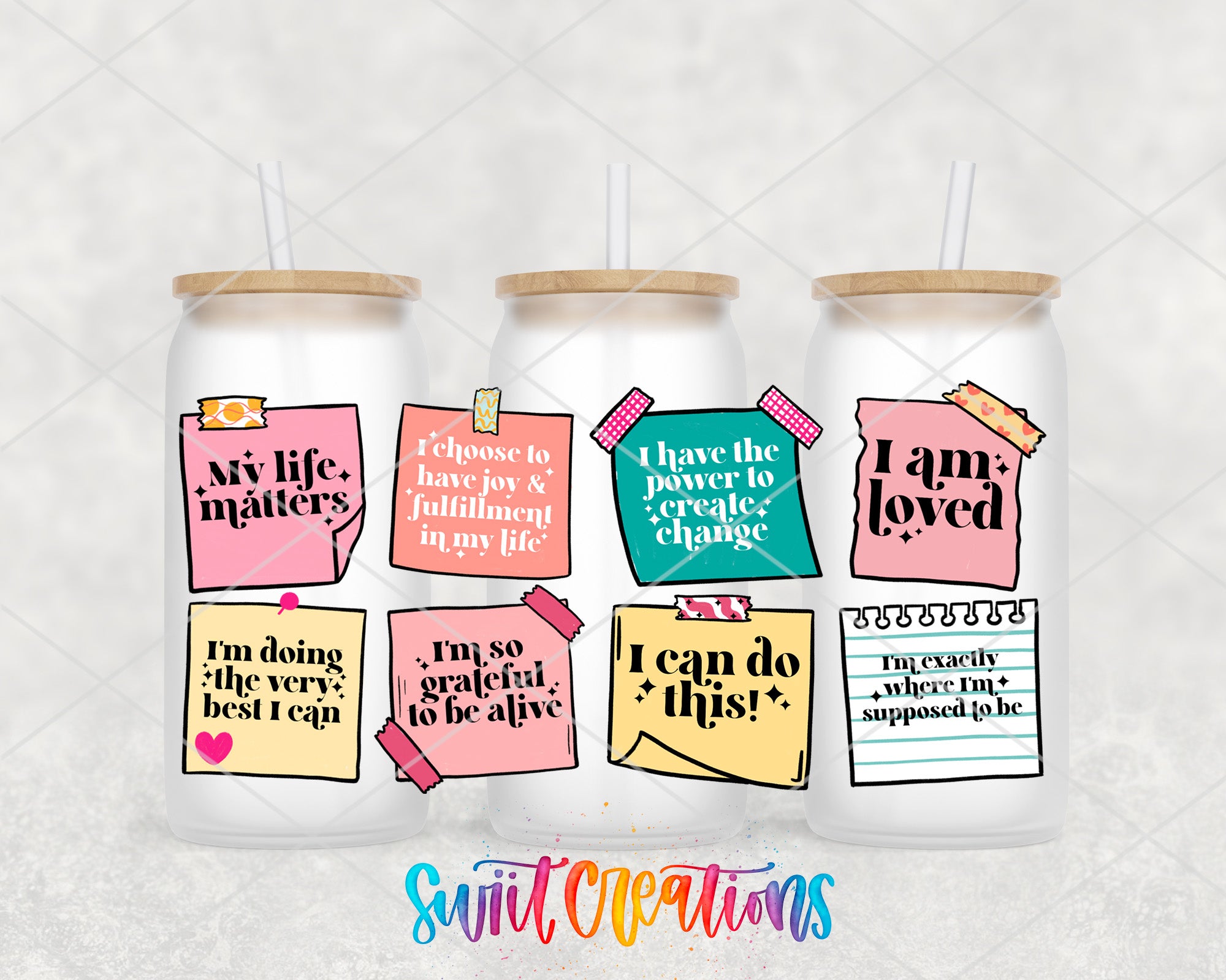 three glass tumblers with colorful stickers and text on them, arranged in a row.