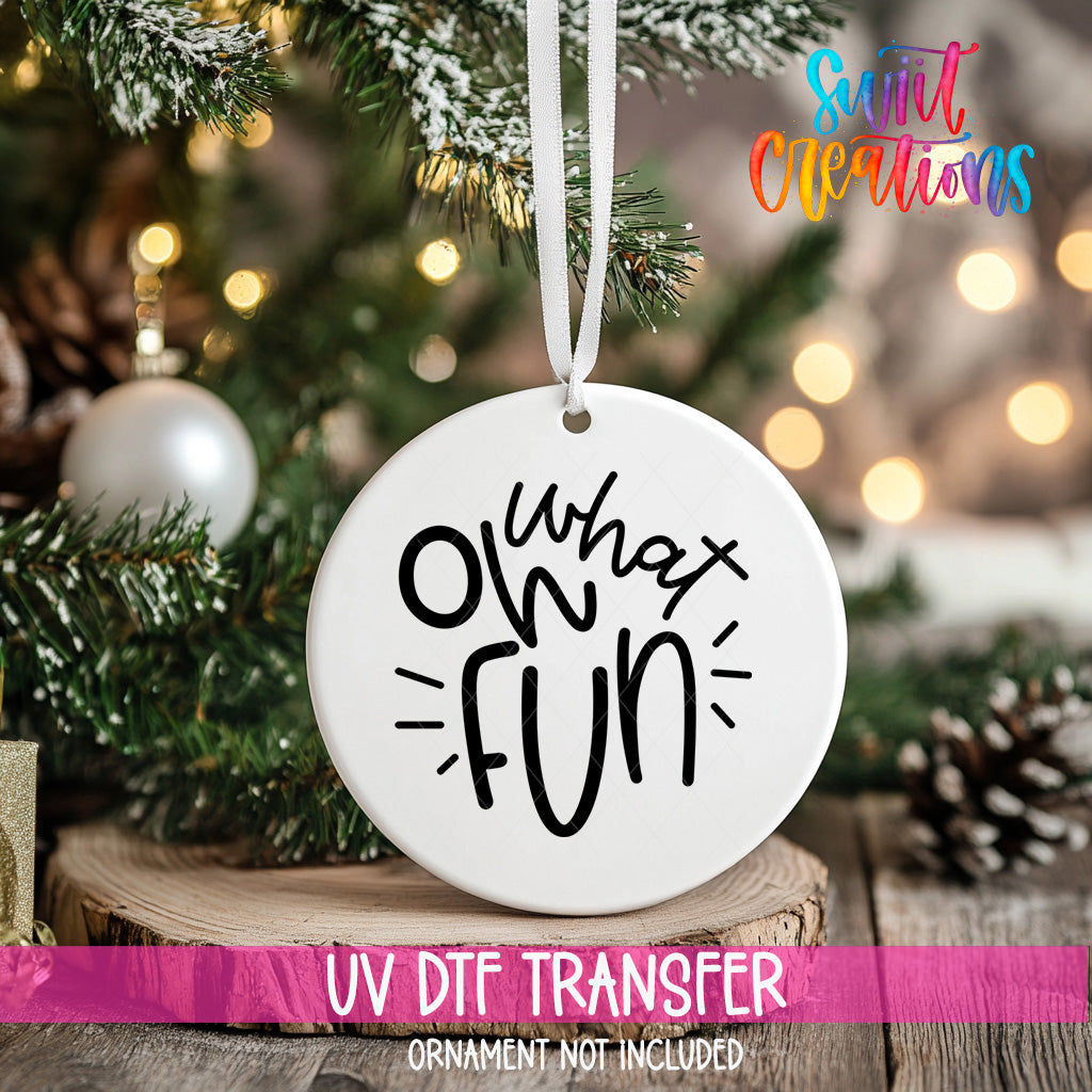 A white ornament with the text "oh what fun" hanging from a Christmas tree.