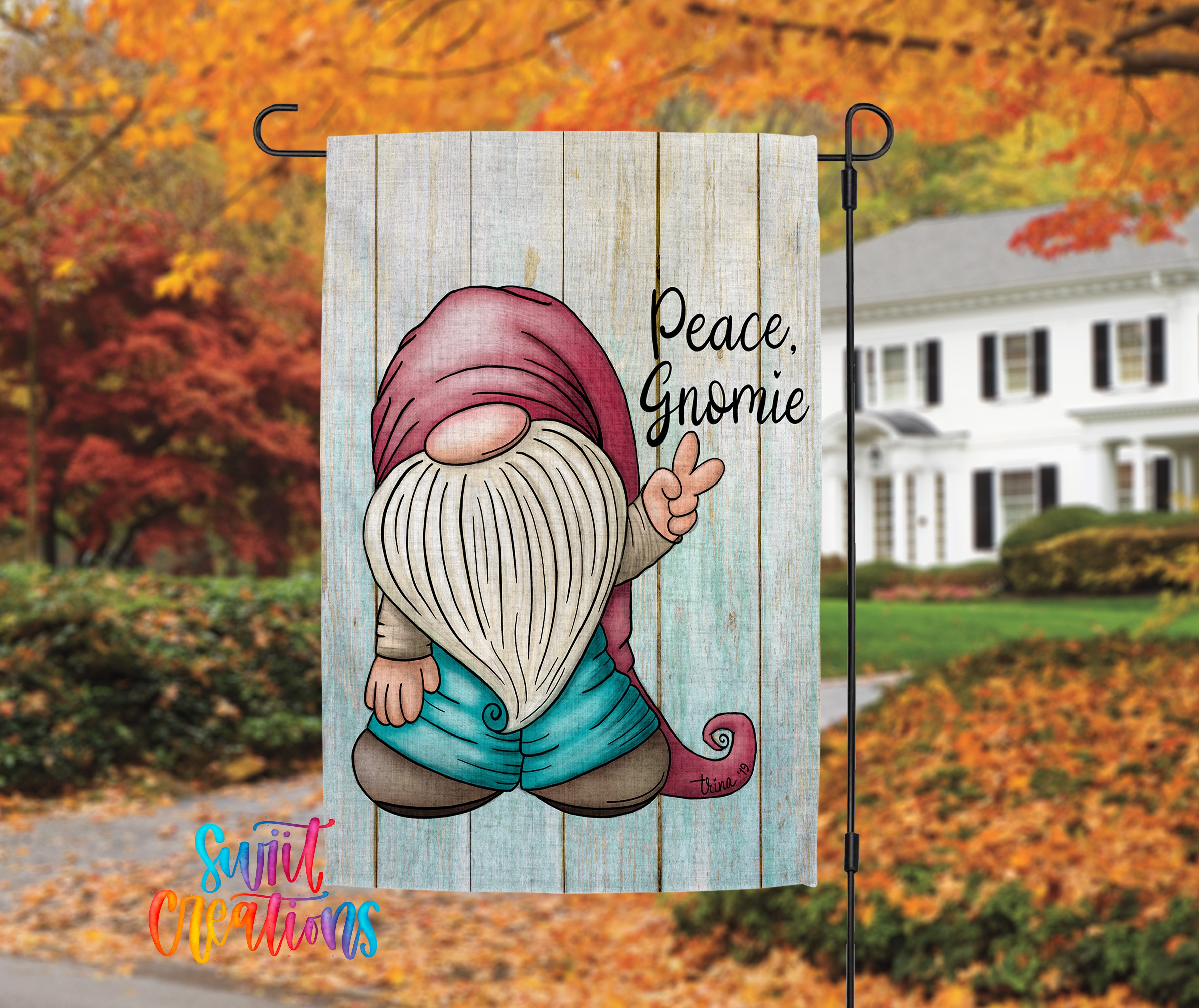 A colorful garden gnome sign with the text "Peace, Gnomeie" is displayed in front of a house with autumn foliage in the background.