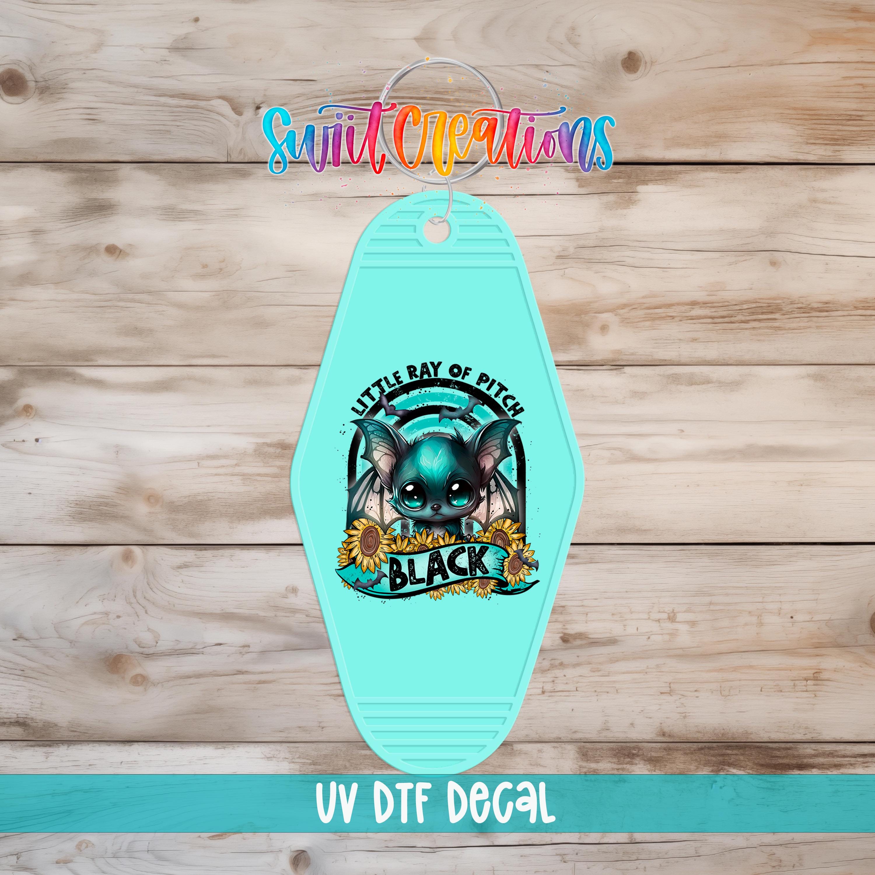 A turquoise keychain with a bat and sunflower design, featuring the text "Little Ray of Pitch" and "Black" on it.