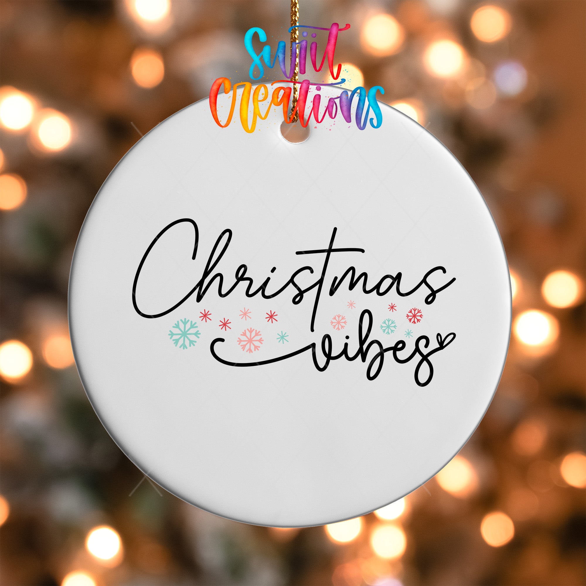 A white ornament with the text "Christmas vibes" written on it, hanging against a background of colorful lights.