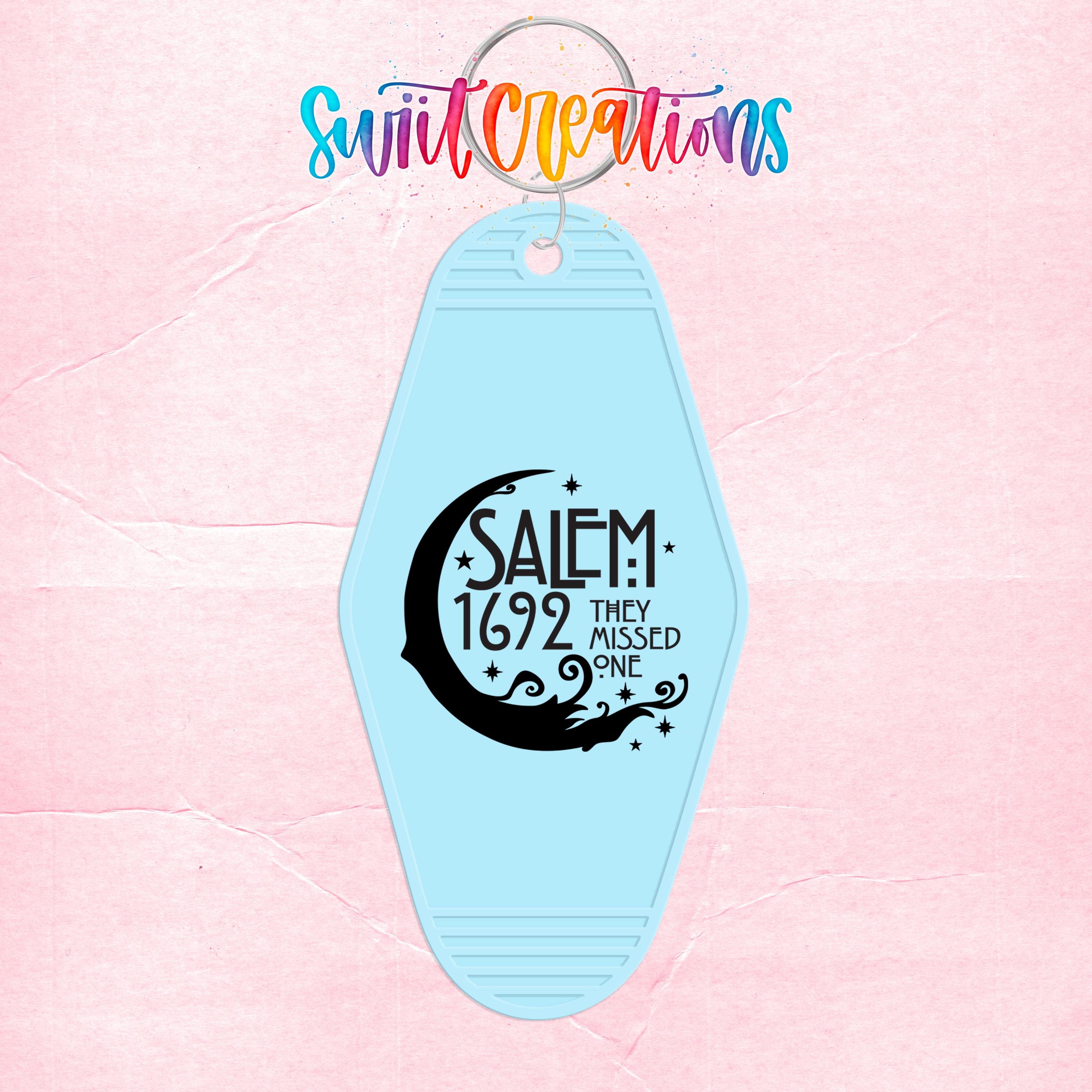 A blue keychain with a design featuring a crescent moon and stars, along with the text "SALEM 1692 THEY MISSED ONE" printed on it.