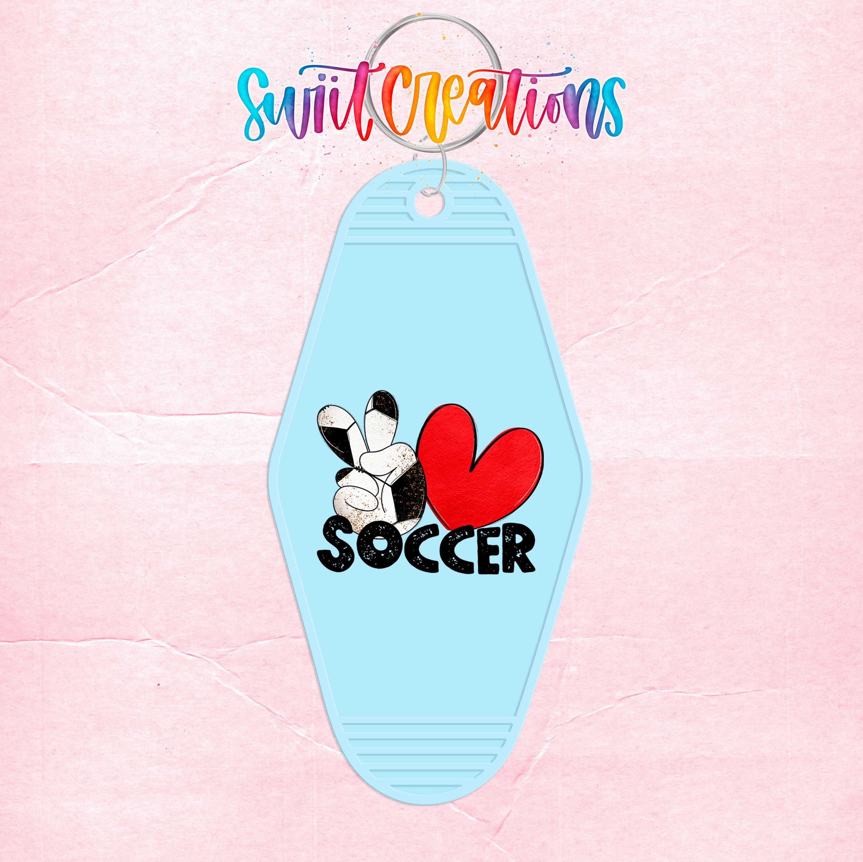 A keychain with a soccer-themed design, featuring a red heart and the word "SOCCER" written in black letters.