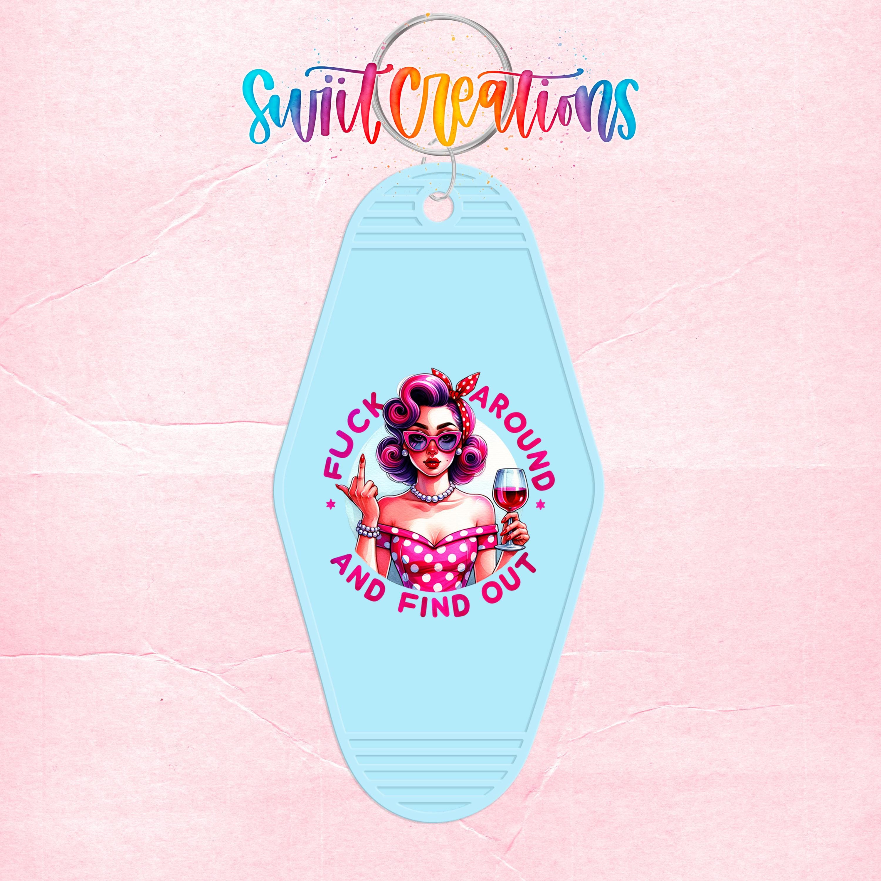 A keychain with a pink and blue design featuring a woman with curly hair and sunglasses, holding a wine glass and making a peace sign. The text on the keychain says "FUCK AROUND AND FIND OUT".