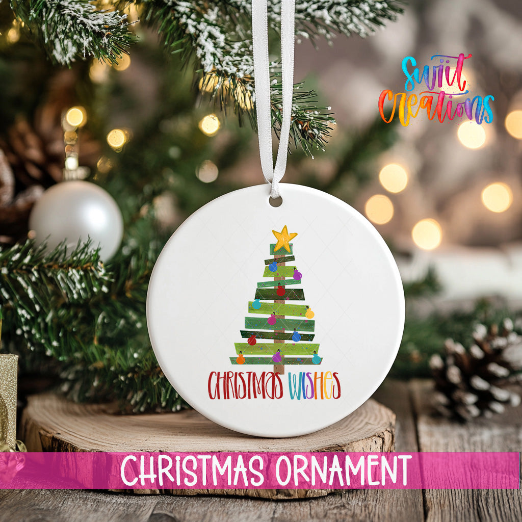 A white Christmas ornament with a tree design hangs on a tree branch, surrounded by other Christmas decorations and lights.