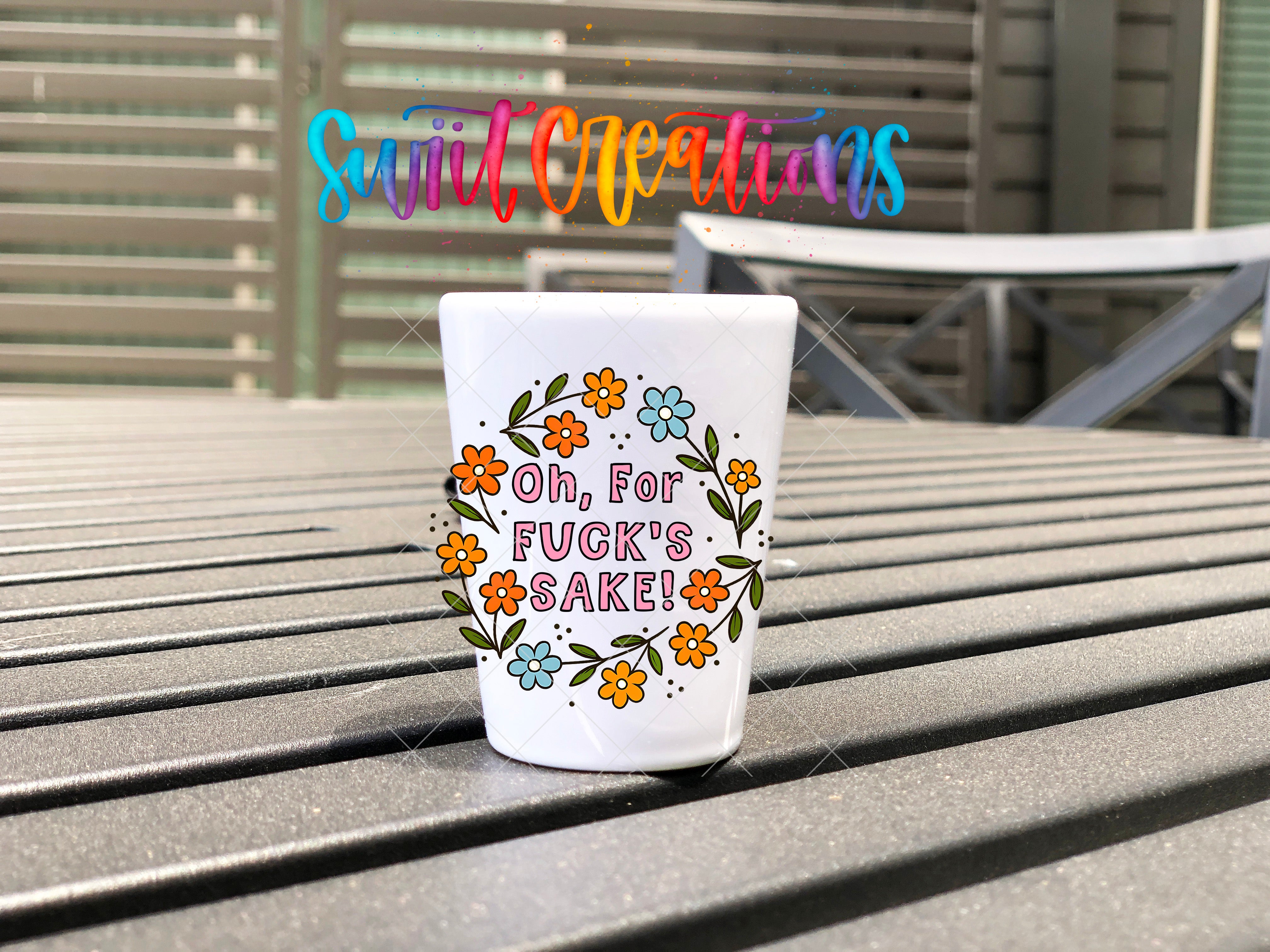 A white mug with a colorful floral design and text on it, placed on a wooden surface.