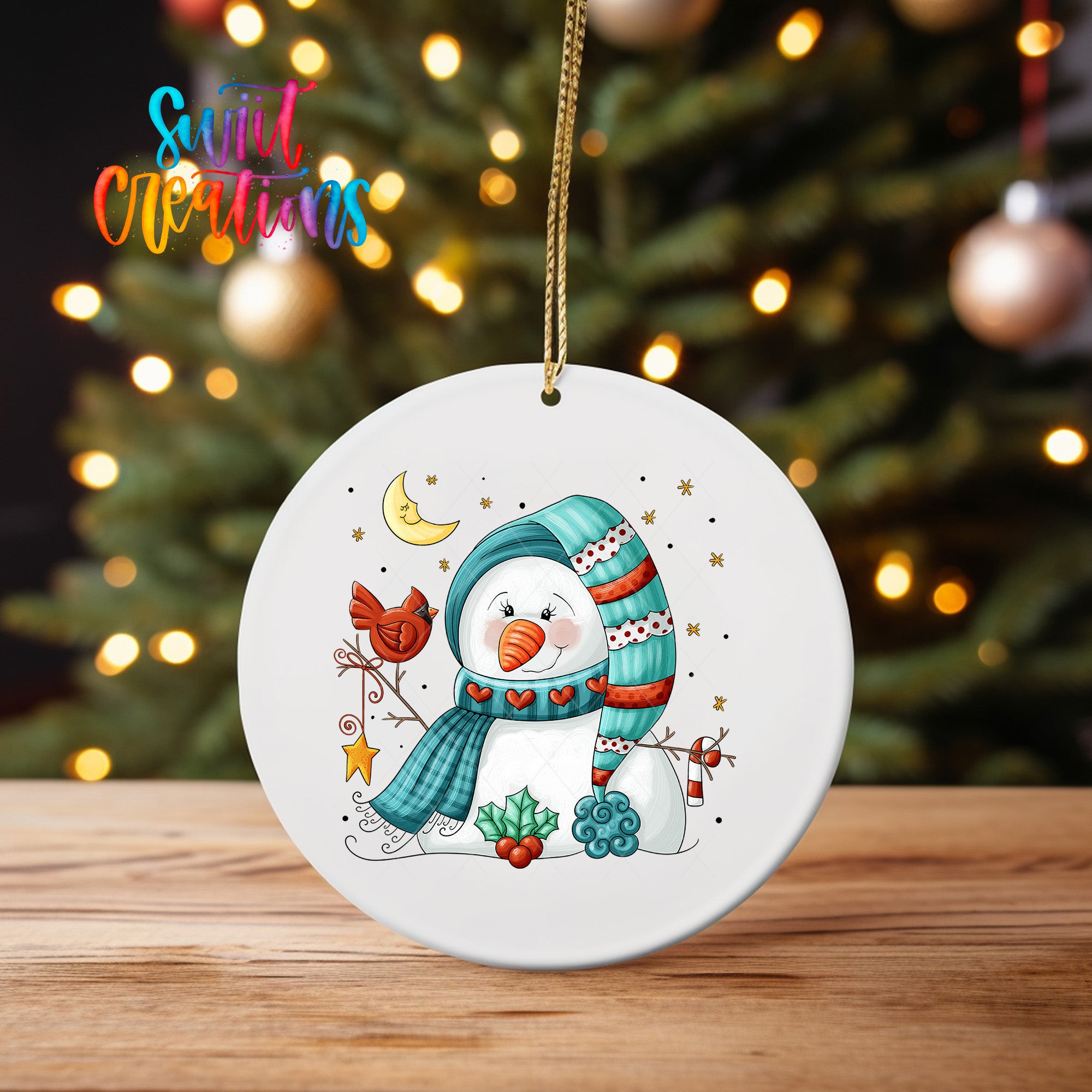 A white ornament featuring a snowman with a scarf, a bird, and other winter-themed elements, hanging on a string against a blurred background of Christmas lights.