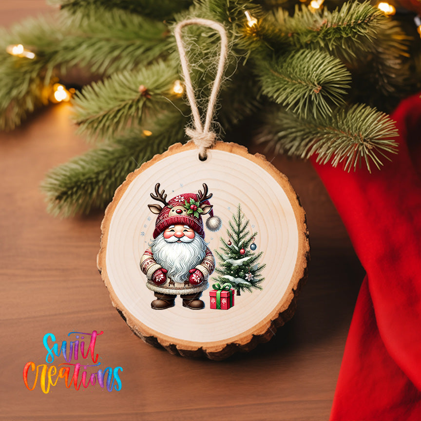 A wooden ornament featuring a Santa Claus figure with antlers and a Christmas tree, hanging on a Christmas tree with lights visible in the background.