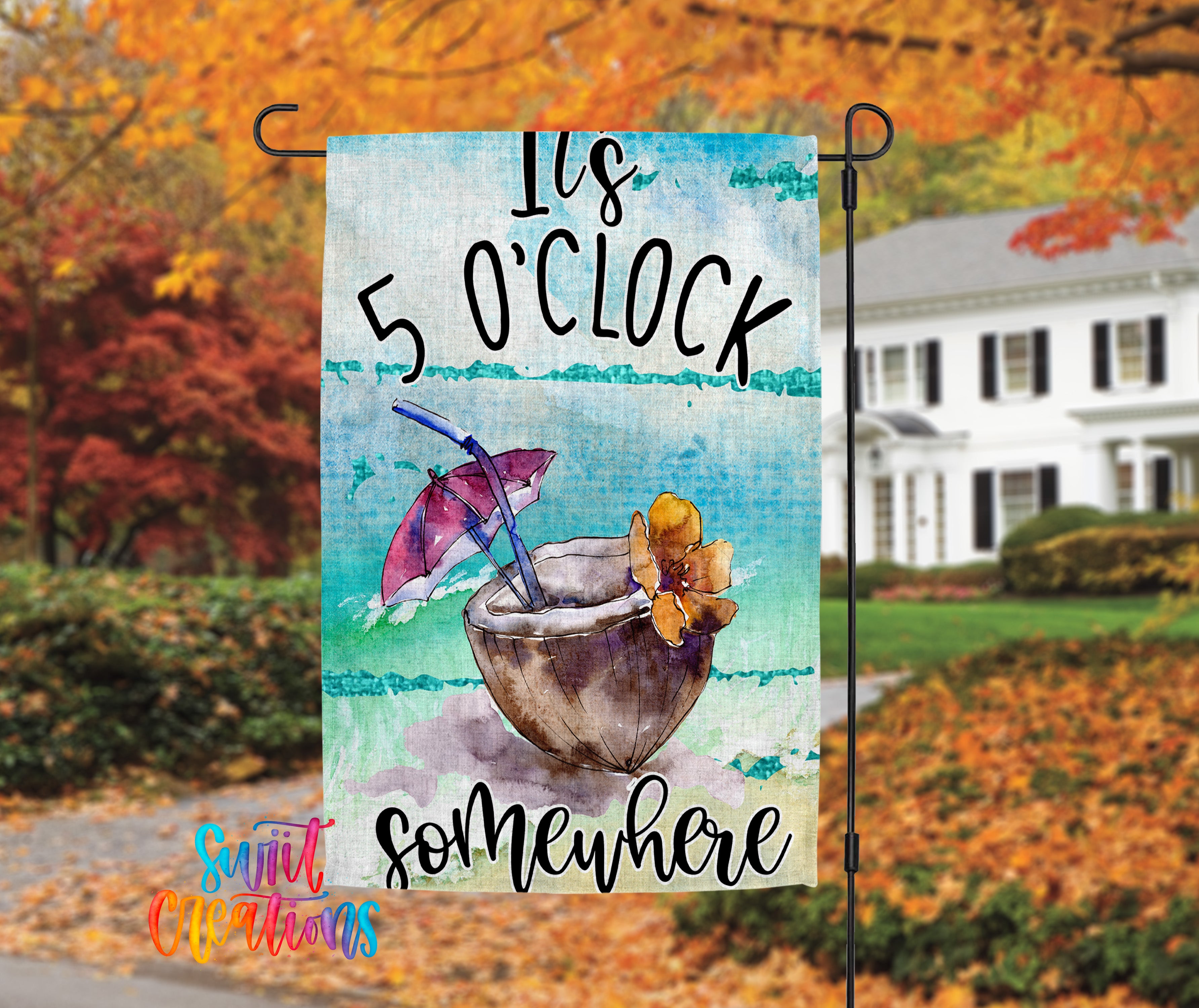 A colorful banner with a tropical drink and umbrella, hanging in front of a house with autumn foliage in the background.