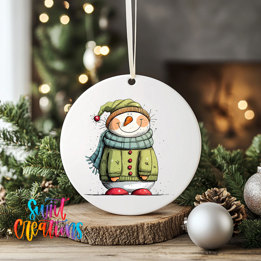 A white ceramic ornament featuring a snowman with a scarf and hat, surrounded by Christmas decorations such as pine cones and ornaments.