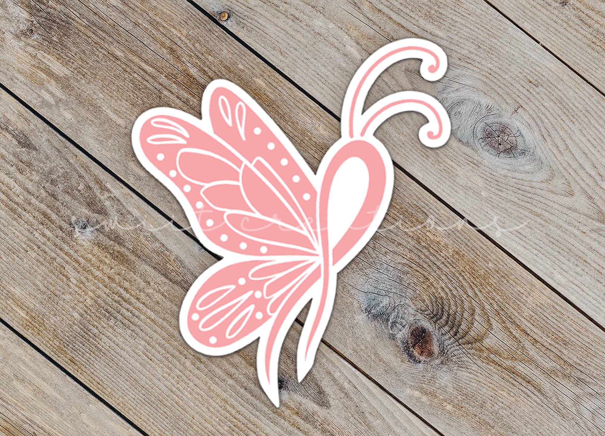 a pink butterfly sticker sitting on top of a wooden floor