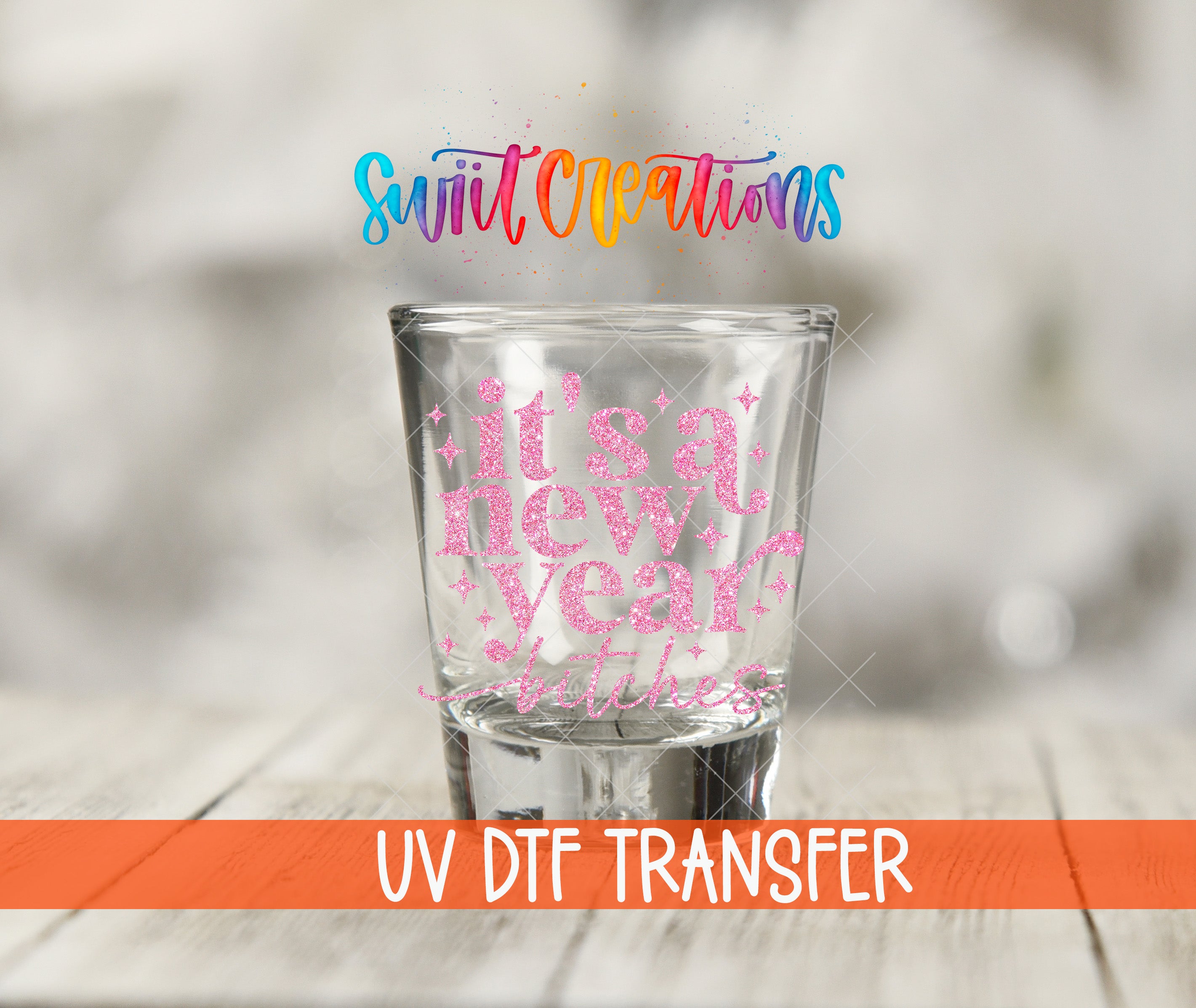 A glass with a pink glittery design on it, placed on a wooden surface.