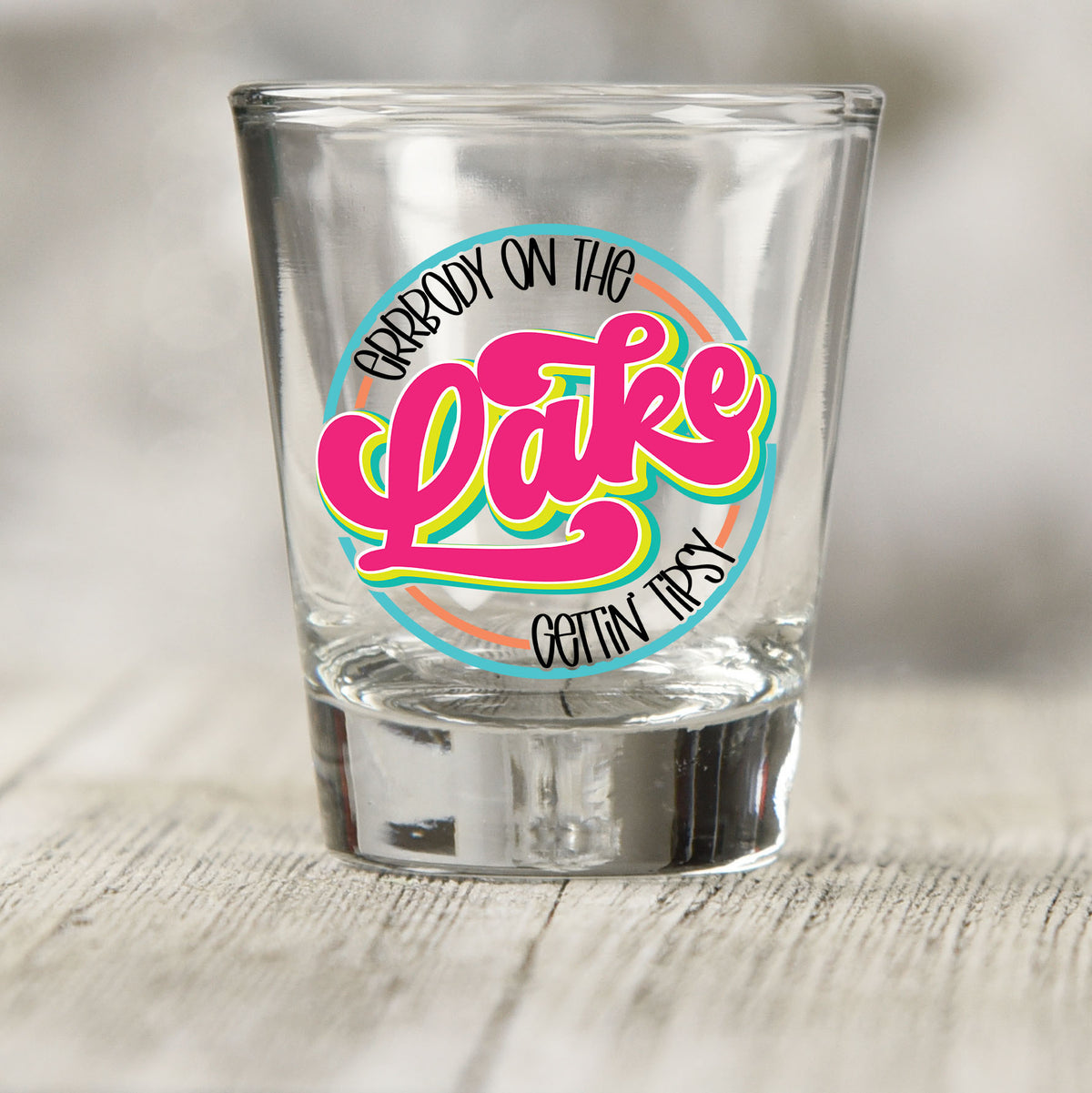 Everybody on the Lake Gettin Tipsy shot glass UV DTF transfer with retro script inside a circle on a clear shot glass