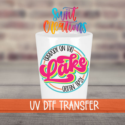 Everybody on the Lake Gettin Tipsy UV DTF transfer on a white shot glass in front of a brick wall