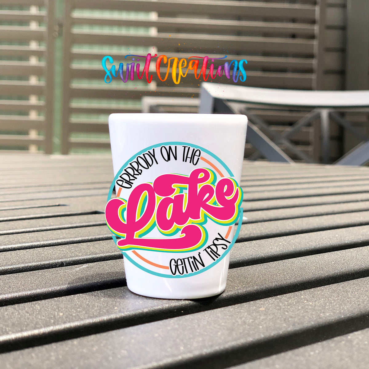 Everybody on the Lake Gettin Tipsy UV DTF transfer on a white shot glass on an outdoor patio table