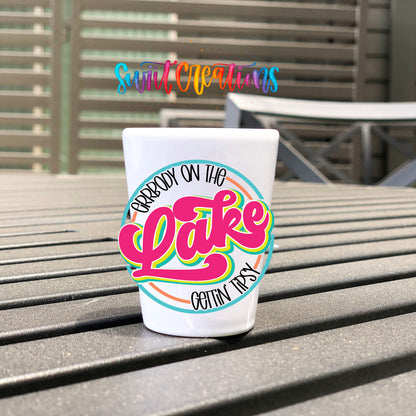 Everybody on the Lake Gettin Tipsy UV DTF transfer on a white shot glass on an outdoor patio table