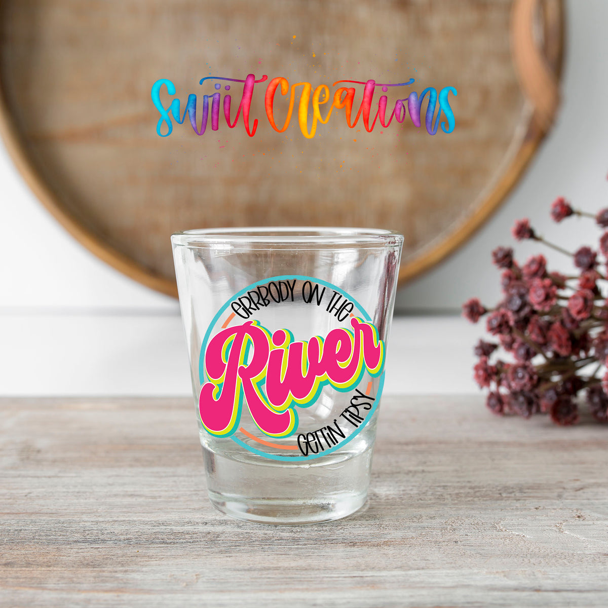 Everybody on the River Gettin Tipsy shot glass transfer on a clear glass beside a wooden barrel and dried flowers