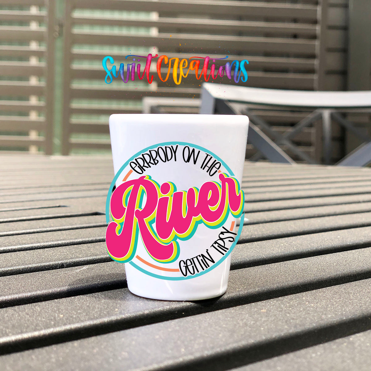 Everybody on the River Gettin Tipsy UV DTF transfer on a white shot glass on an outdoor patio table