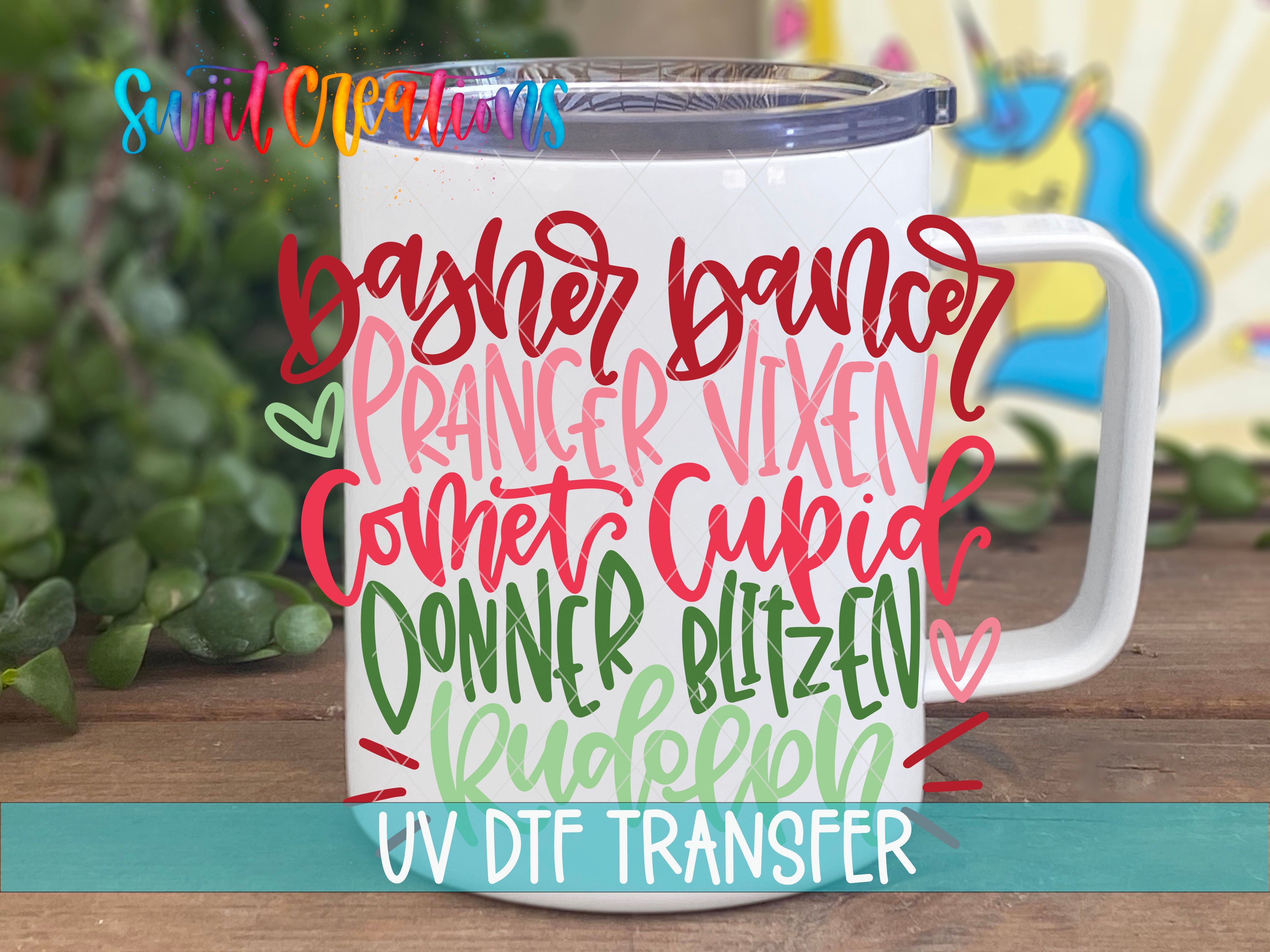 A white mug with colorful text printed on it, placed on a wooden surface with greenery in the background.